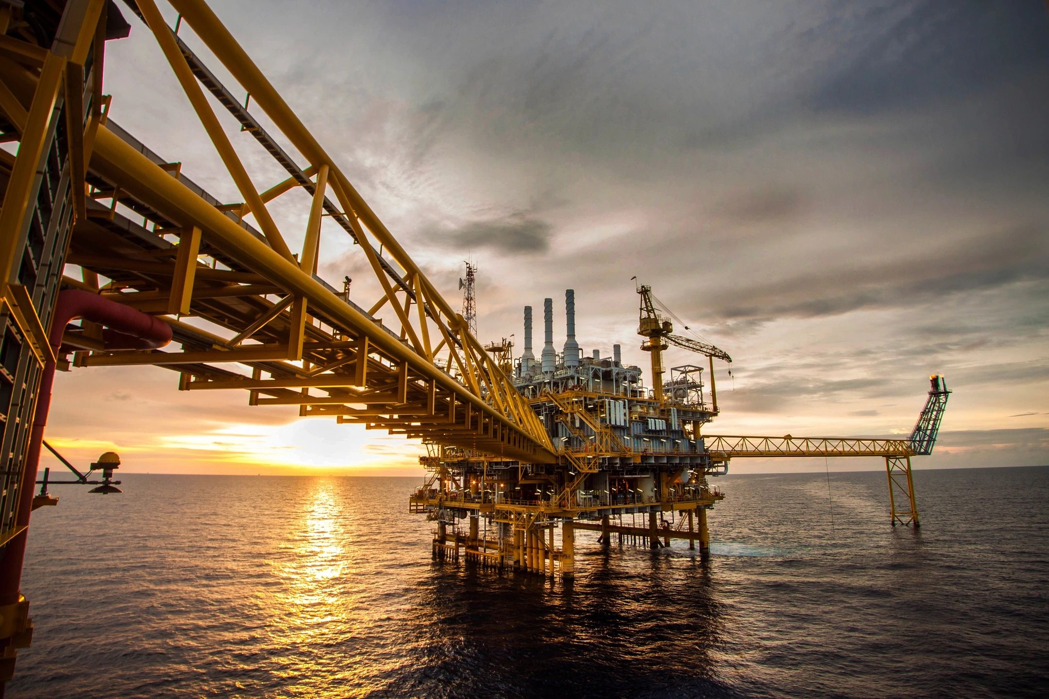Offshore oil platform at sunset representing sustainable production operations in the energy industry
